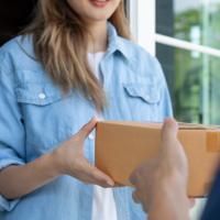 Woman accepts a small package from a delivery person.