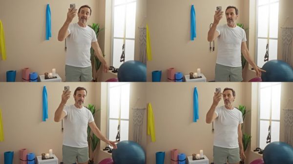西班牙裔男性在現(xiàn)代水療中心通過視頻通話享受健康課程，周圍有瑜伽墊和裝飾，突顯放松與溝通。