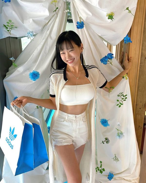 a person holding a shopping bag stands in front of a decorated backdrop