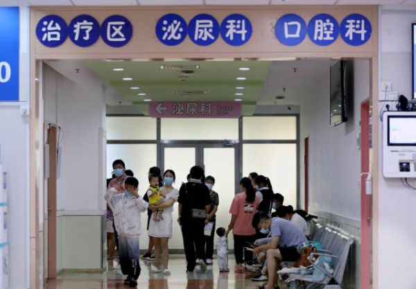 家长带着患儿在诊室外候诊。图源：新华社