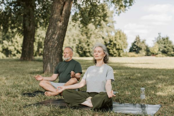 Man and woman meditating in park to celebrate National Wellness Month