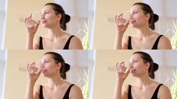 年轻的白人女性在瑜伽练习后喝水。愉快的早晨，家中的健康生活。瑜伽教练和指导员正在休息。