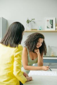 Two women discuss a meal plan together in a bright, modern kitchen, illustrating the supportive relationship between a nutritional therapist in Raleigh, NC and someone exploring disordered eating therapy in Asheville, NC.