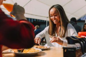 Smiling woman enjoying a meal outdoors, representing a positive relationship with food through nutrition therapy in Raleigh, NC and support from a dietitian in Hendersonville, NC.