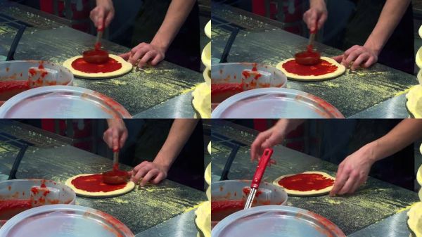 Pizzaiolo正在制作一个小披萨，添加番茄酱，并将其涂在披萨店的面团上
