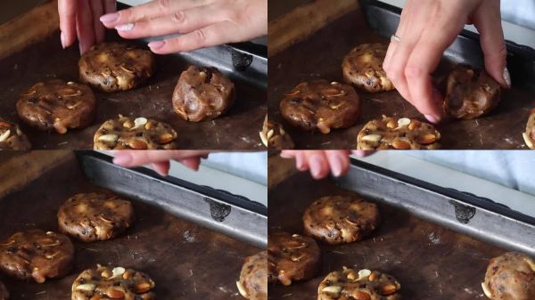 一位女性正在制作健康餅干，里面有堅(jiān)果和巧克力。她正在塑形面團(tuán)。餅干面團(tuán)被擺放在烤盤上。特寫鏡頭。