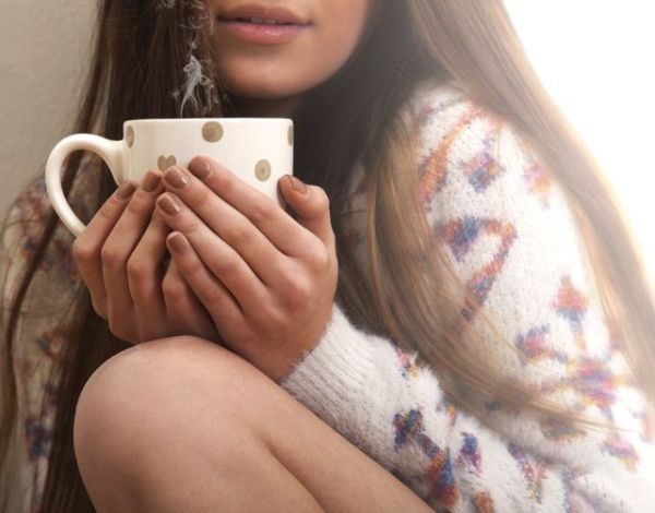 女性が両手でマグカップを持っている画像