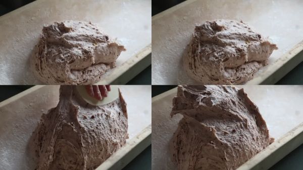 手部特寫：用刮刀在木托盤中塑形面團。