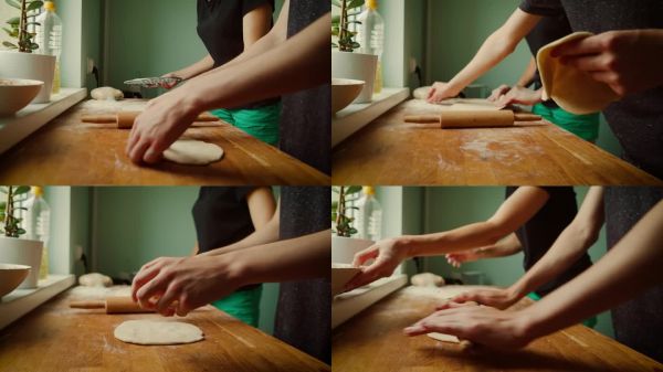 在木質(zhì)表面上準(zhǔn)備面團的手，同時握著餃子模具。將面團壓平以便塑形為餃子。