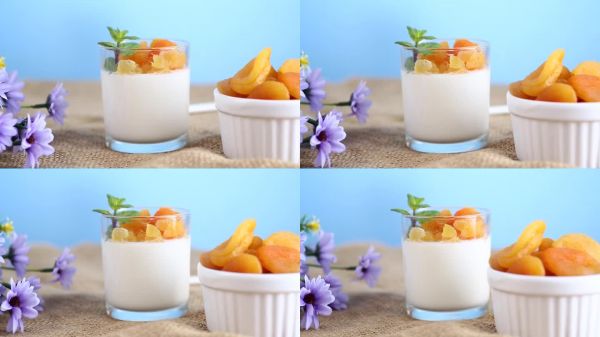 深色木桌上的輕盈水果酸奶配干杏。