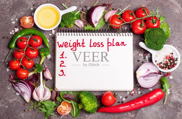 新鲜有机蔬菜，香草和香料。将沙拉、番茄、辣椒、大蒜混合在一起，打开空白的笔记本，计划饮食。减肥的概念。促进新陈代谢的产品。煮健康的食物照片摄影图片