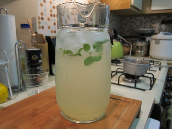 一位女性正在玻璃杯中放入新鲜柠檬片并倒入温水