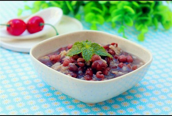 一位年轻女性坐在阳台小桌前享用荔枝和绿豆糖水