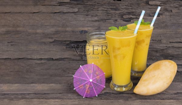 芒果冰沙黄色彩色果汁饮料健康高蛋白的木制背景。照片摄影图片