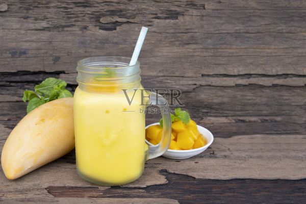 芒果冰沙黄色的彩色果汁奶昔混合饮料健康高蛋白的味道美味在玻璃饮料减肥饮料情节早上在木制背景。照片摄影图片
