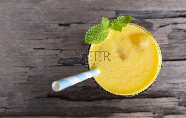 芒果冰沙多彩果汁奶昔混合饮料健康高蛋白美味在玻璃饮料减肥饮料孤立的木材背景从顶部视图。照片摄影图片