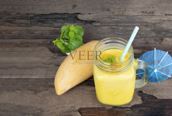 芒果冰沙汁橙汁奶昔混合饮料健康高蛋白的味道美味的玻璃集饮料早上在木头背景。照片摄影图片