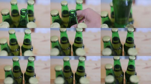 女人的手在厨房台面上挑选冰镇啤酒，周围有很多冰冷的啤酒瓶。