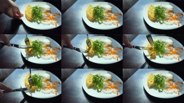 一盤食物，有黃色的煎蛋卷和綠葉蔬菜。盤子是白色的，食物擺放整齊。