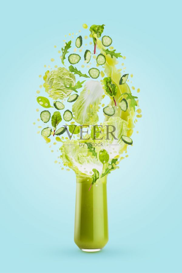 杯中盛有新鮮的綠色蔬菜汁，伴有飛舞的綠葉、黃瓜片，果汁飛濺，在藍色背景上爆裂流淌。健康維生素飲品，適合排毒飲食、健身菜單、素食。照片攝影圖片