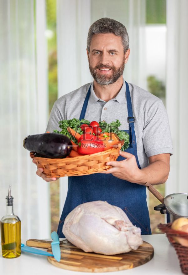身穿圍裙的男人，秋季菜單，準備健康晚餐，廚師烹飪蔬菜，感恩節(jié)晚餐，男人烹飪食物，烹飪火雞和蔬菜用于感恩節(jié)，有機食品照片攝影圖片