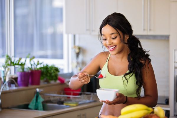 happy-woman-eating-fruit-at-kitchen-after-a-work-out-healthy-lifestyle-tips