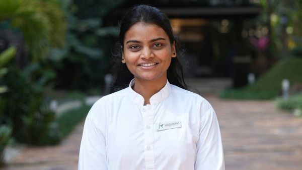 身穿白色制服、佩戴姓名牌的印度女子在戶外花園環(huán)境中。