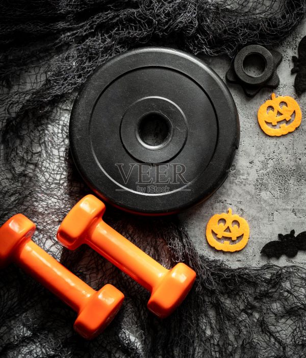 哑铃与万圣节装饰品。健康健身生活方式俯视图。健身房锻炼、运动训练概念。照片摄影图片