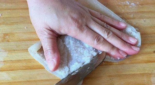 家庭厨房场景：手部特写操作低速螺旋榨汁机，左侧不锈钢盆盛放冰镇紫甘蓝丝，右侧玻璃碗盛放去皮西红柿块，机器出汁口正流入刻度玻璃杯