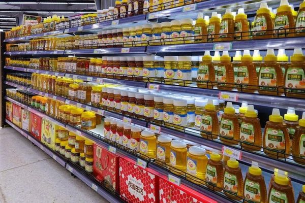 超市冷柜中陳列的多品類蜂蜜產(chǎn)品對比圖：有機(jī)認(rèn)證洋槐蜜、野生百花蜜、濃縮麥盧卡UMF10+、蜂王漿混合蜜，標(biāo)簽清晰可見產(chǎn)地、等級、活性指標(biāo)與有機(jī)標(biāo)識(shí)