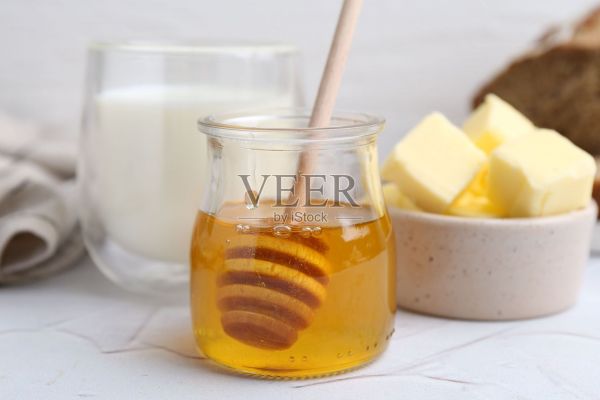 白色桌子上的蜂蜜、黄油和牛奶，特写照片摄影图片