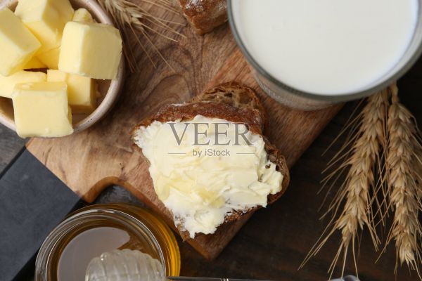 木桌上的美味三明治,配有黄油、蜂蜜和牛奶,俯视图照片摄影图片