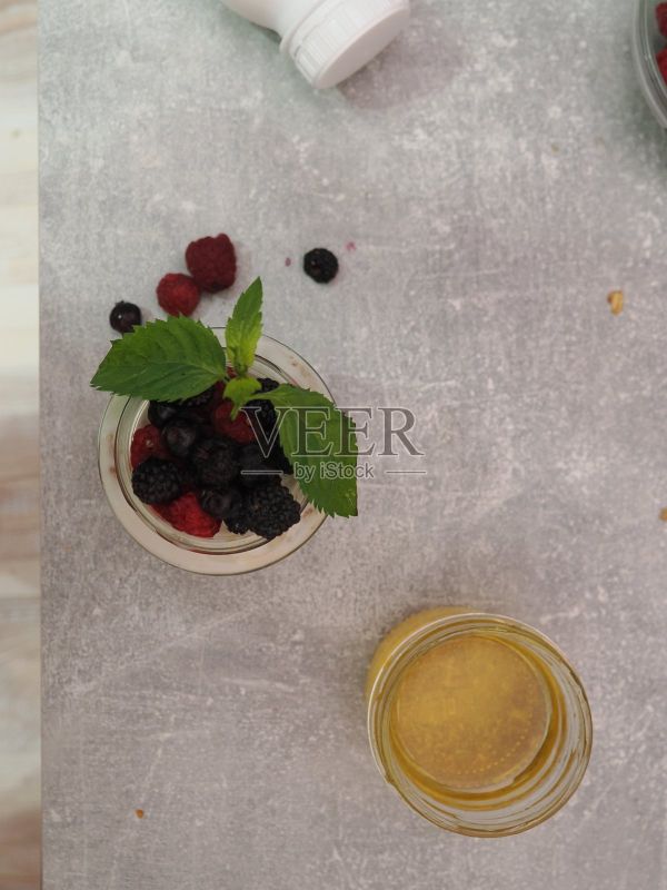 一份健康的早餐，包含酸奶、燕麦片、野莓、覆盆子、蓝莓和蜂蜜，是富含蛋白质的减肥饮食和均衡营养的健身餐。照片摄影图片