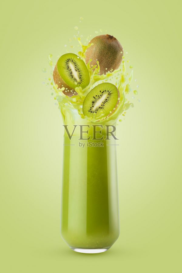 玻璃杯中盛有果肉感的綠色新鮮獼猴桃汁，伴有飛濺的鮮嫩多汁的獼猴桃切片，在綠色背景上飛濺。為健康健身菜單、排毒美食、健康餐點(diǎn)提供的能量維生素水果飲品。照片攝影圖片