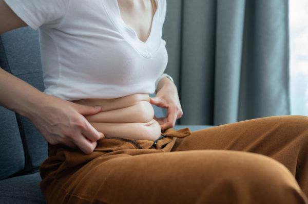 cropped shot of woman touching and squeezing her fat belly