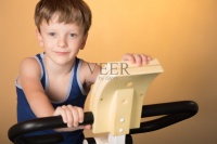 这孩子在健身车上训练。健康的生活方式。图片