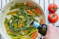 烤蔬菜，芦笋，胡萝卜，迷迭香在煎锅上，用橄榄油和西红柿近，白底俯视图。烹饪，健康生活方式，健康饮食图片