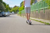 一名穿着休闲运动服的男子骑着电动滑板车。后视图。城市生态理念和健康生活方式图片